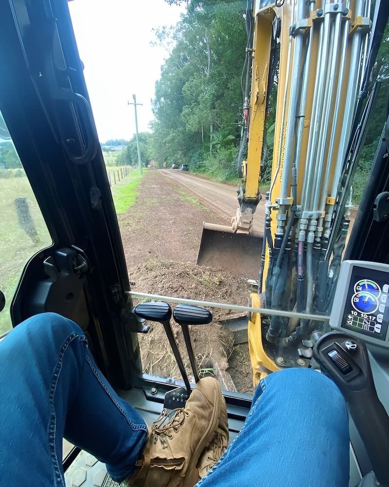 A Person Is Sitting In The Driver's Seat Of An Excavator — Wilsons Excavations & Plant Hire in Gold Coast, QLD