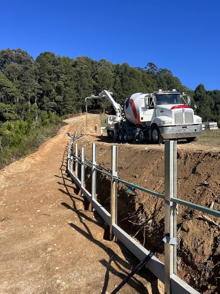 A Concrete Mixer Truck Is Parked On The Side Of A Dirt Road — Wilsons Excavations & Plant Hire in Myocum, NSW