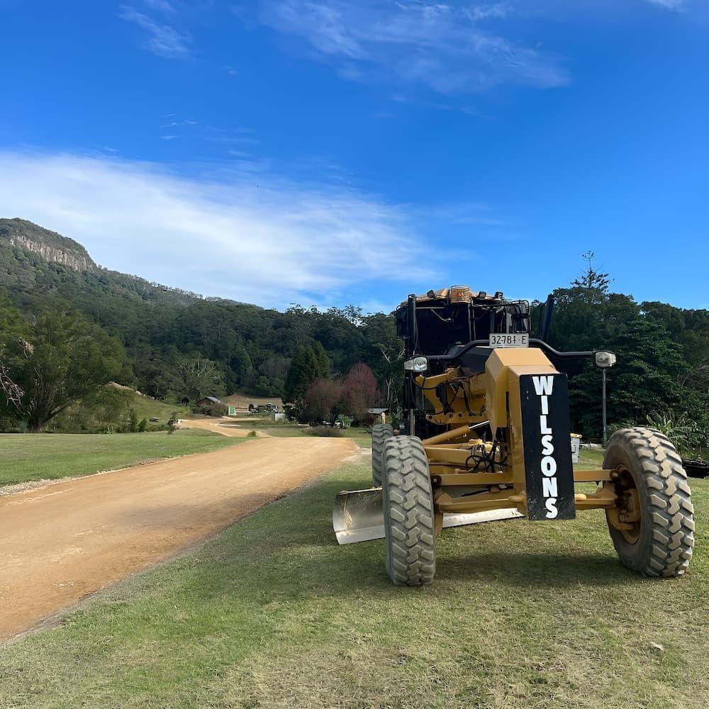 A Bulldozer Is Parked On The Side Of A Dirt Road — Wilsons Excavations & Plant Hire in Pottsville, NSW