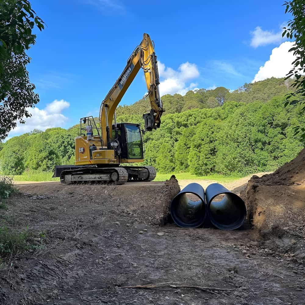 A Yellow Excavator Is Working On A Construction Site — Wilsons Excavations & Plant Hire in Kingscliff, NSW