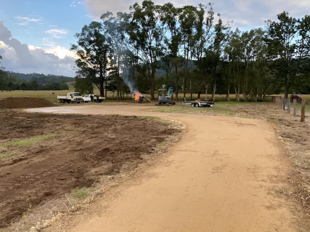 A Dirt Road Going Through A Field With Trees — Wilsons Excavations & Plant Hire in Myocum, NSW