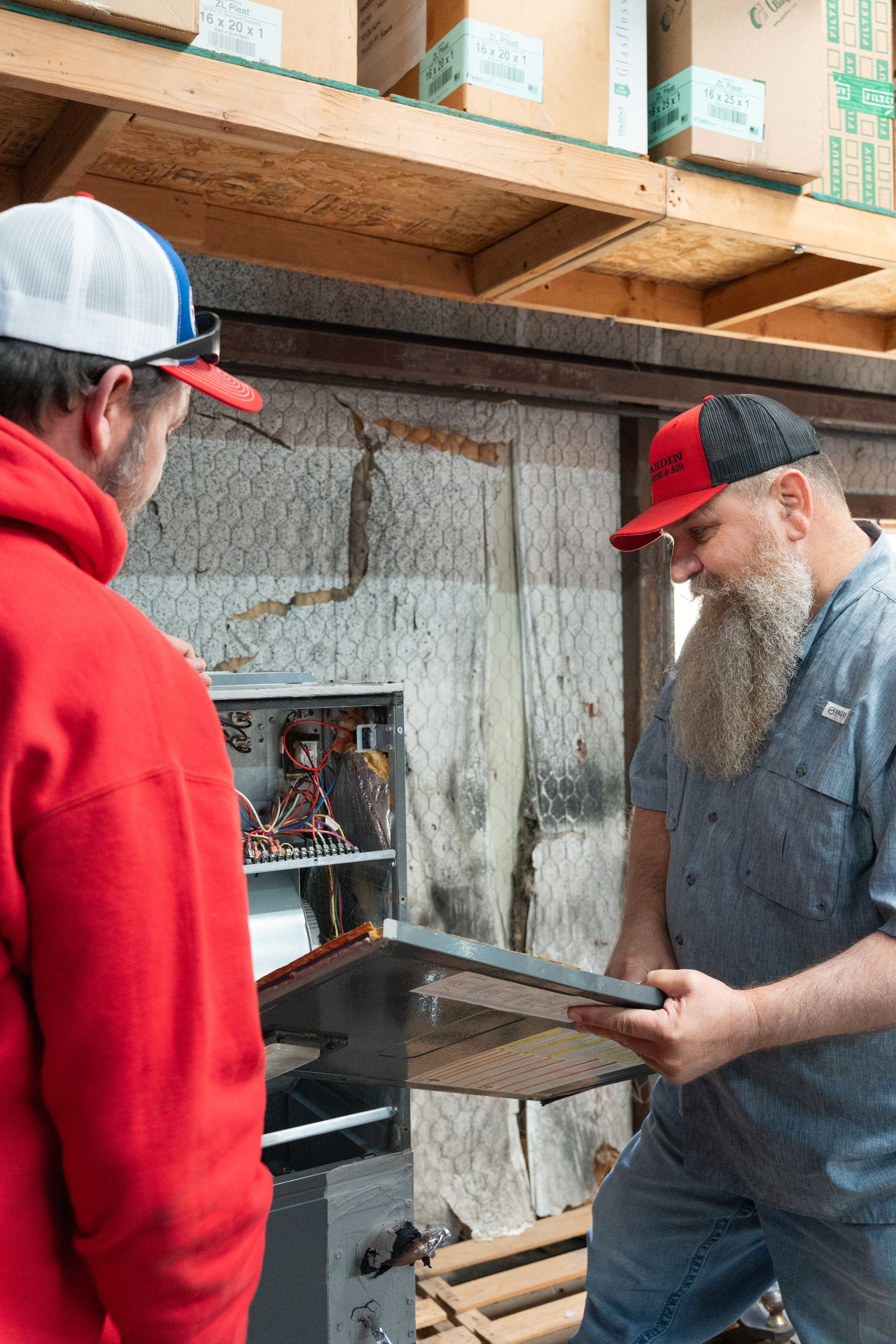 Hardin Heating & Air Technicians inspecting electrical equipment in a warehouse setting.