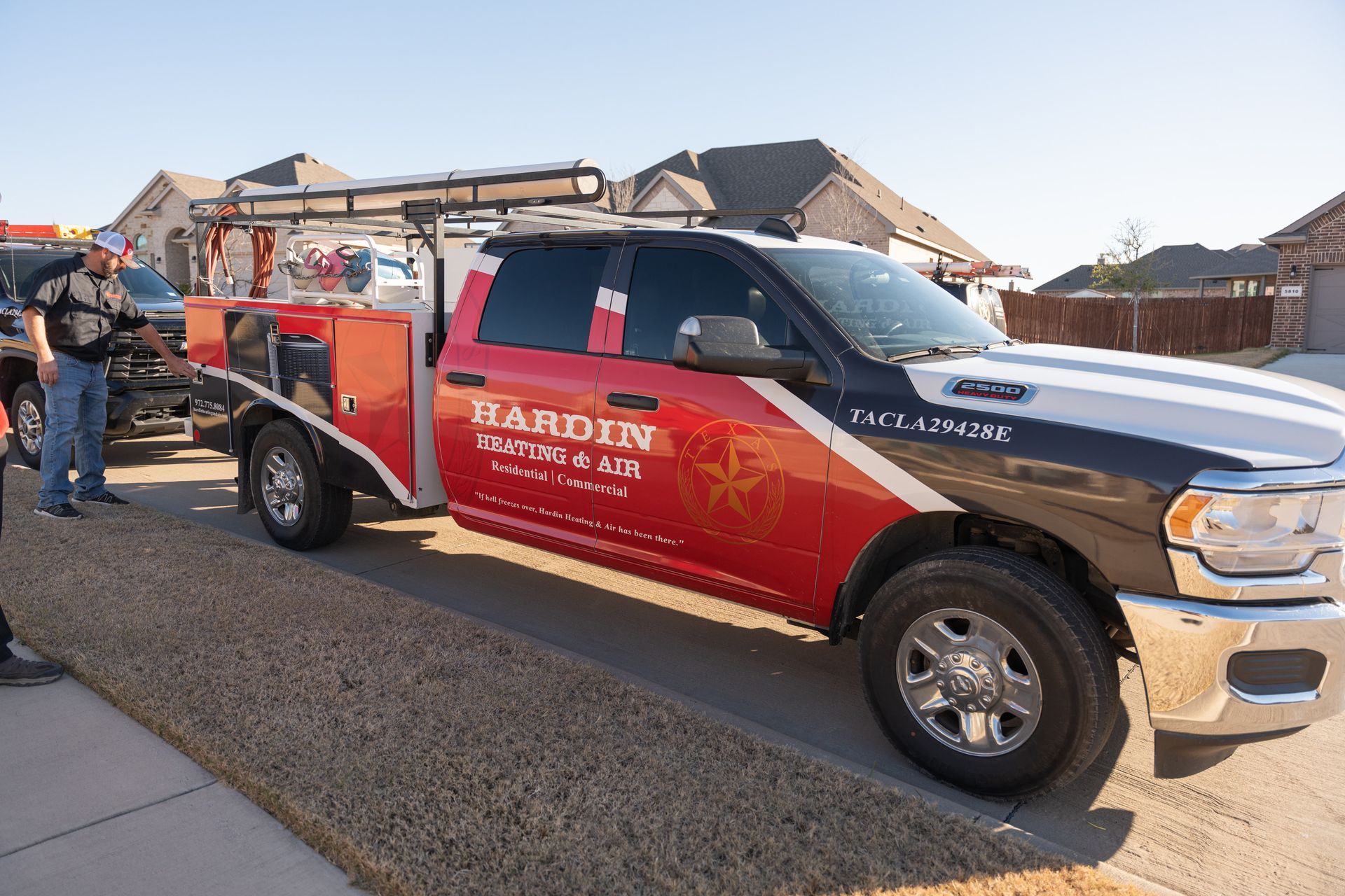Red and black Hardin Roofing truck parked in front of a house, tools on bed.