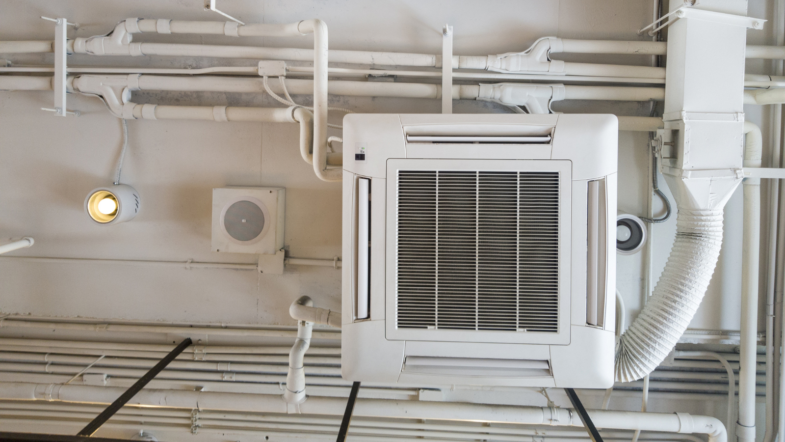 A white air conditioner is hanging from the ceiling of a building.