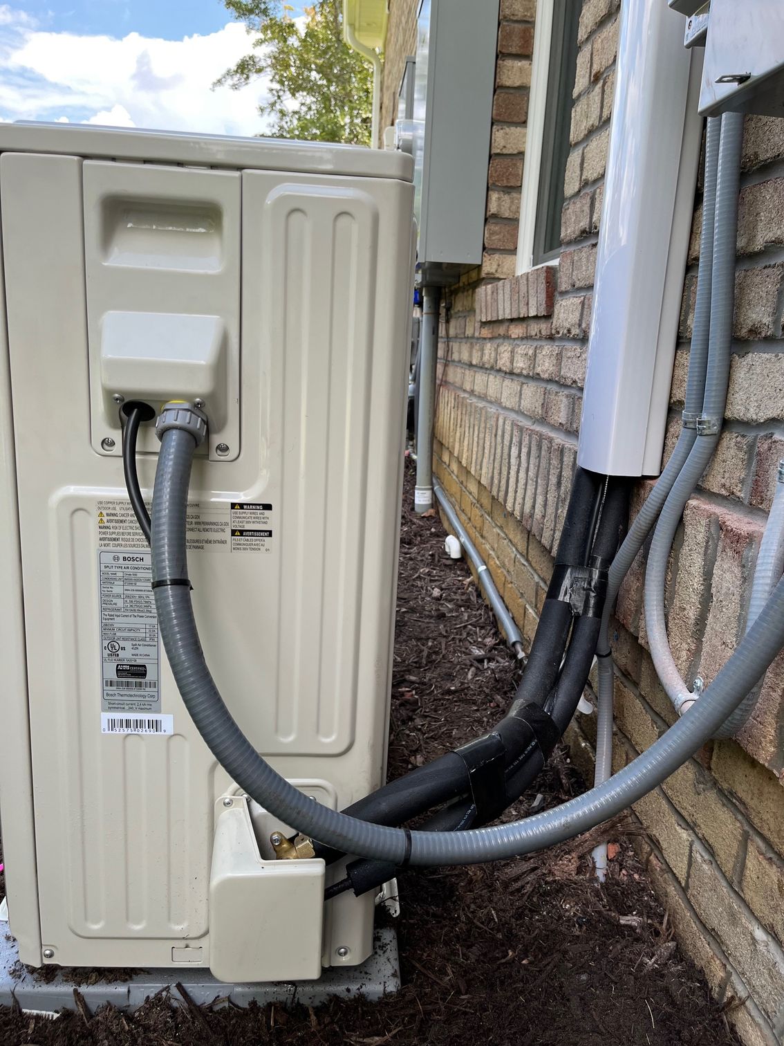 A white air conditioner is sitting on the side of a brick building.