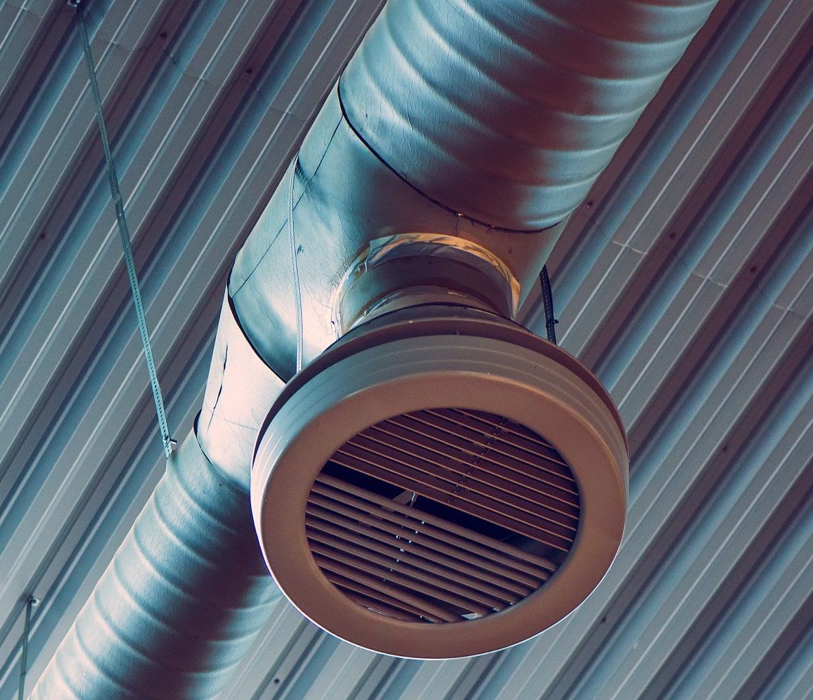 A metal pipe is hanging from the ceiling of a building.