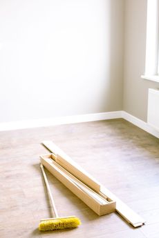 Construction tools on a bare floor in an empty room with white walls and a window