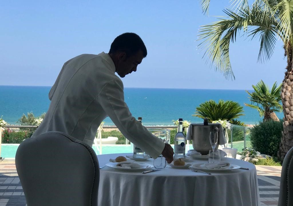 un cameriere in smoking tiene in mano un vassoio con il cibo.