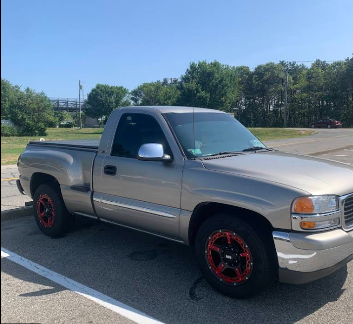 A silver truck with red wheels is parked in a parking lot