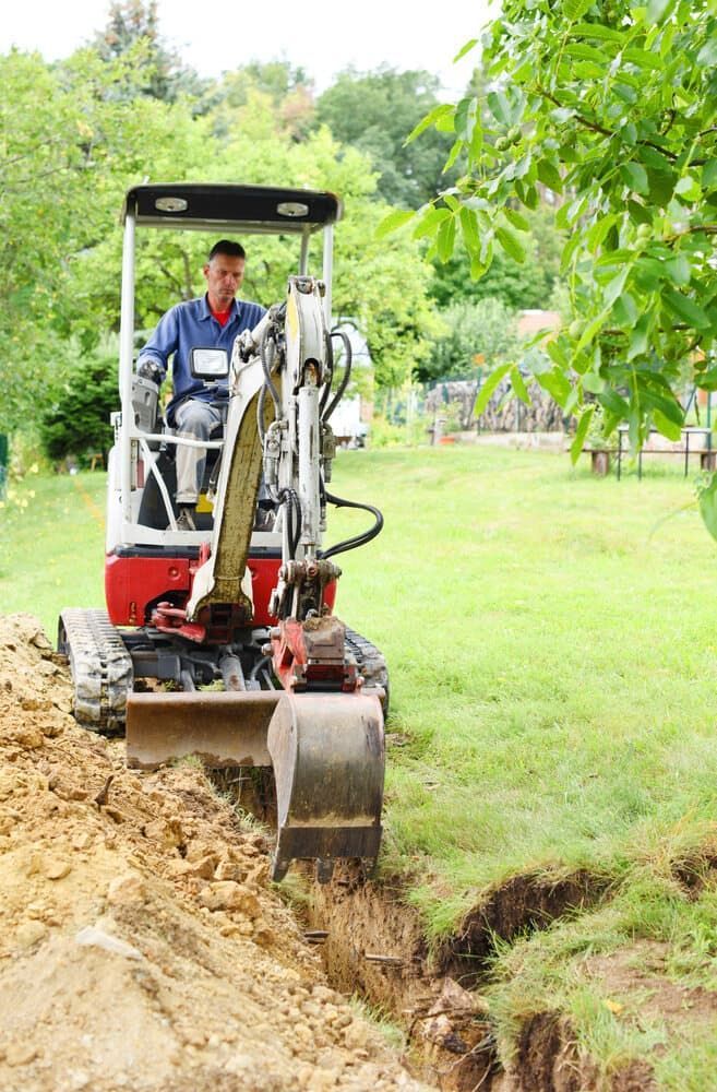 A Man is Driving a Small Excavator in a Yard — Matt's Mini Machines in Bli Bli, QLD
