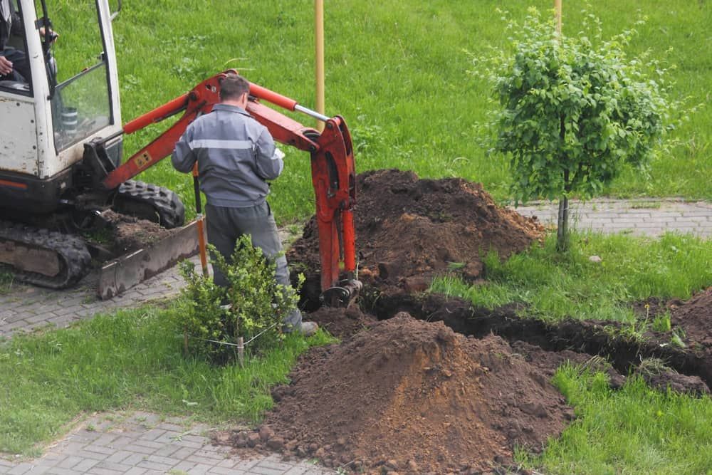 A Man is Using a Small Excavator to Dig a Hole in the Ground — Matt's Mini Machines in Yandina, QLD