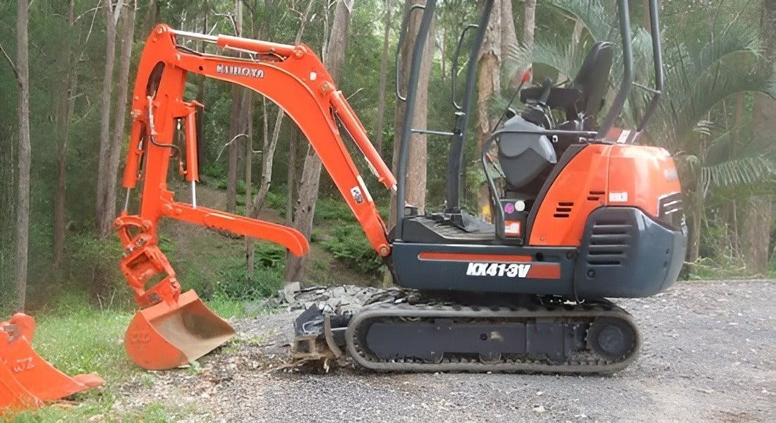 A Small Orange and Black Excavator is Parked on a Gravel Road — Matt's Mini Machines in Buderim, QLD
