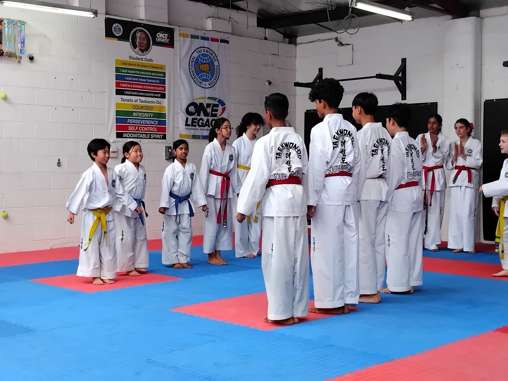 Karate class in a dojo, students in white gis standing on blue and red mats