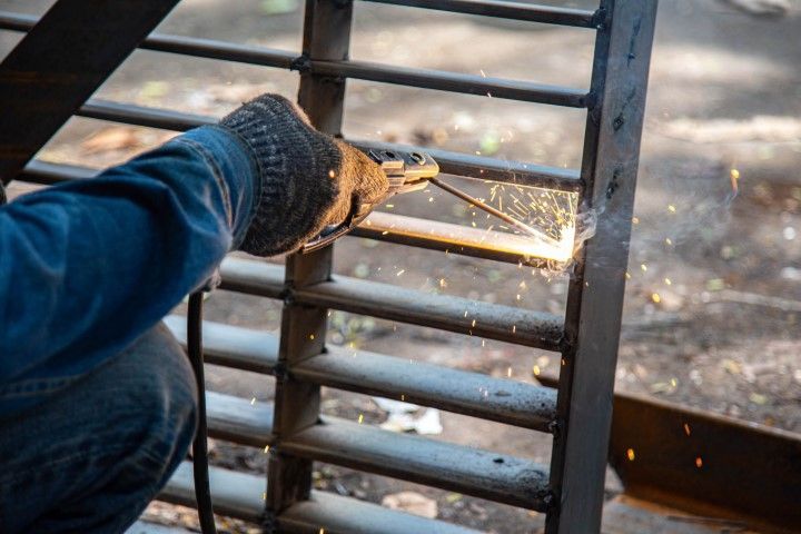 Person welding a metal gate, sparks flying.