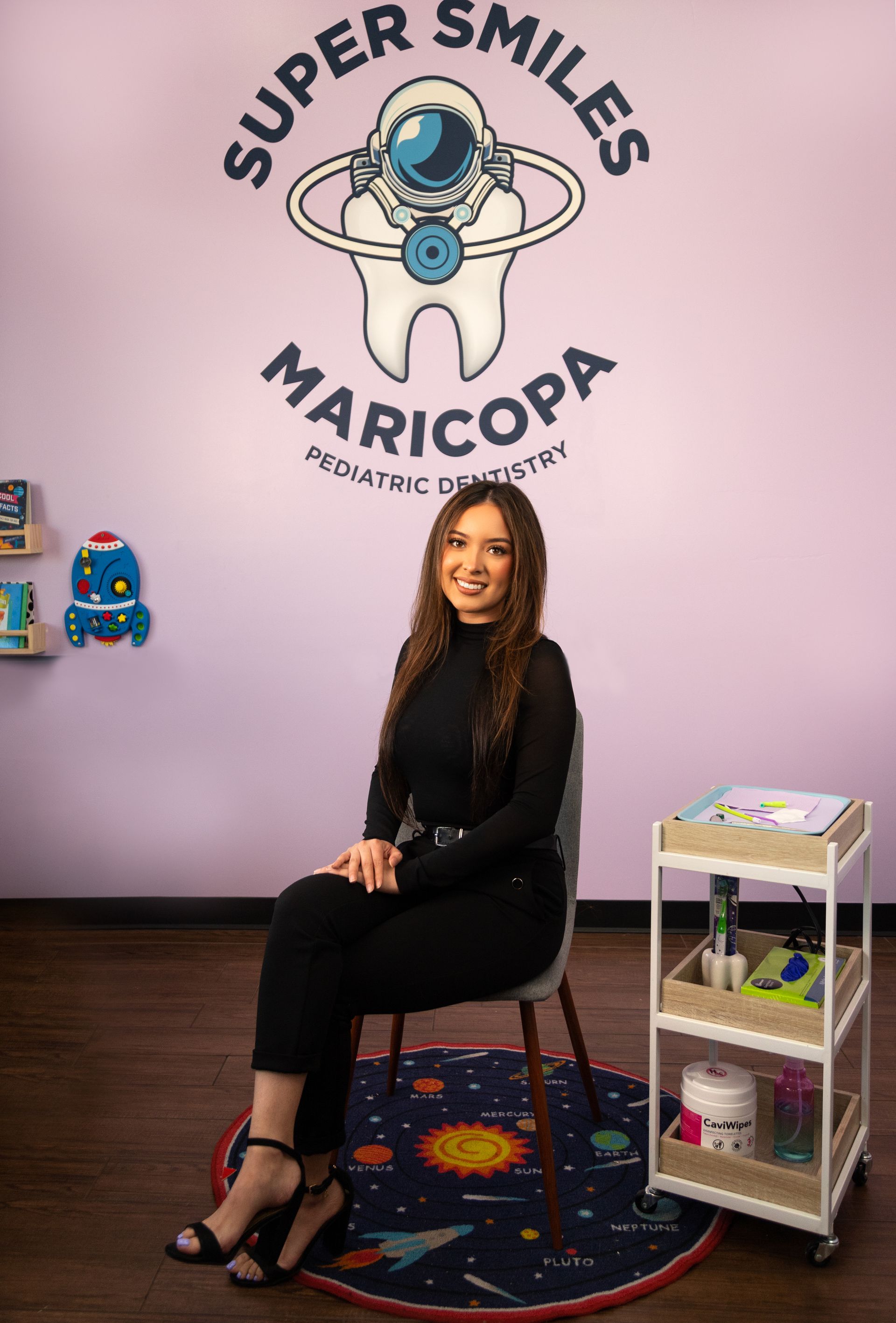 A woman is sitting in a chair in front of a wall with a tooth on it.