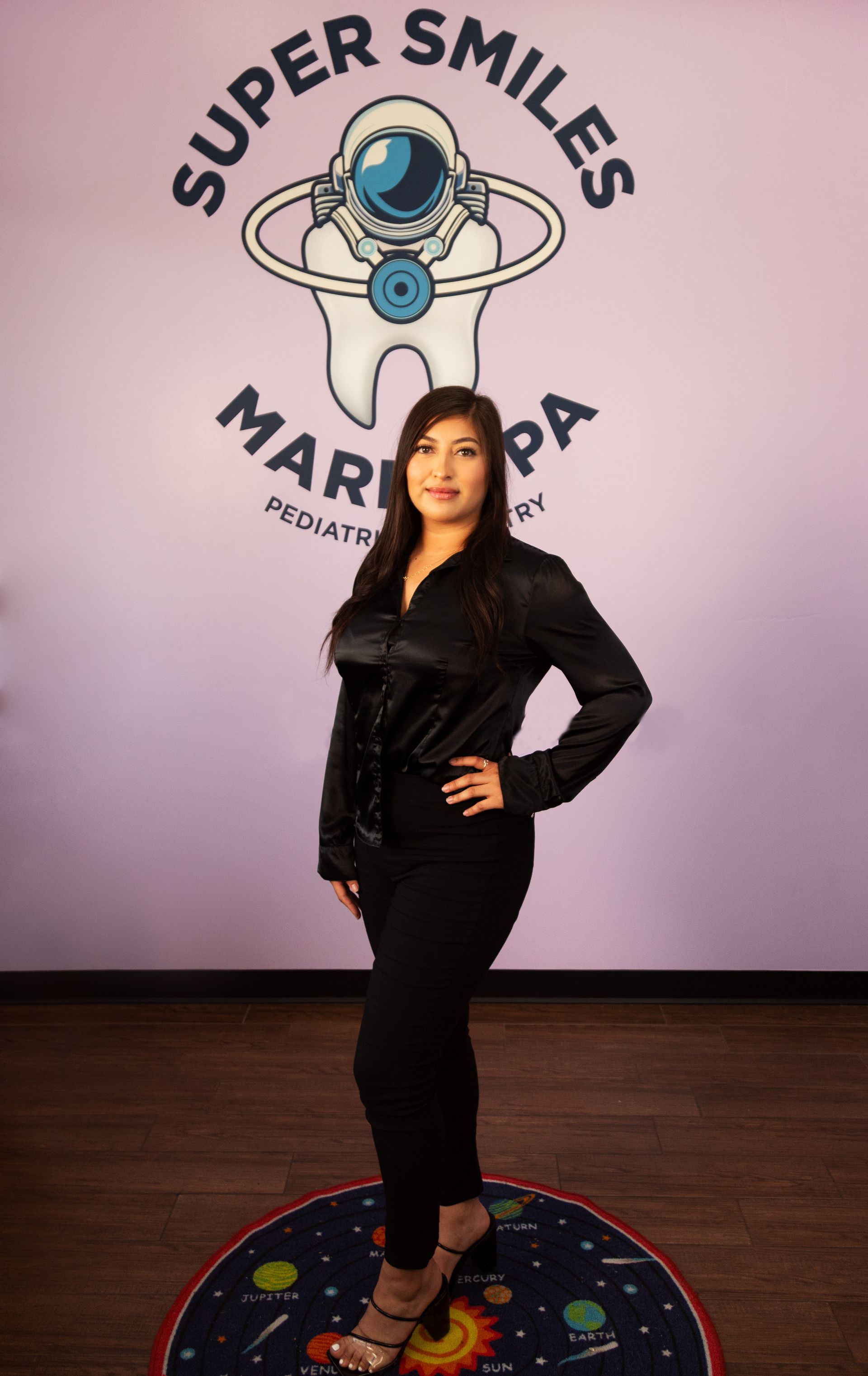 A woman is standing in front of a sign that says super smiles.