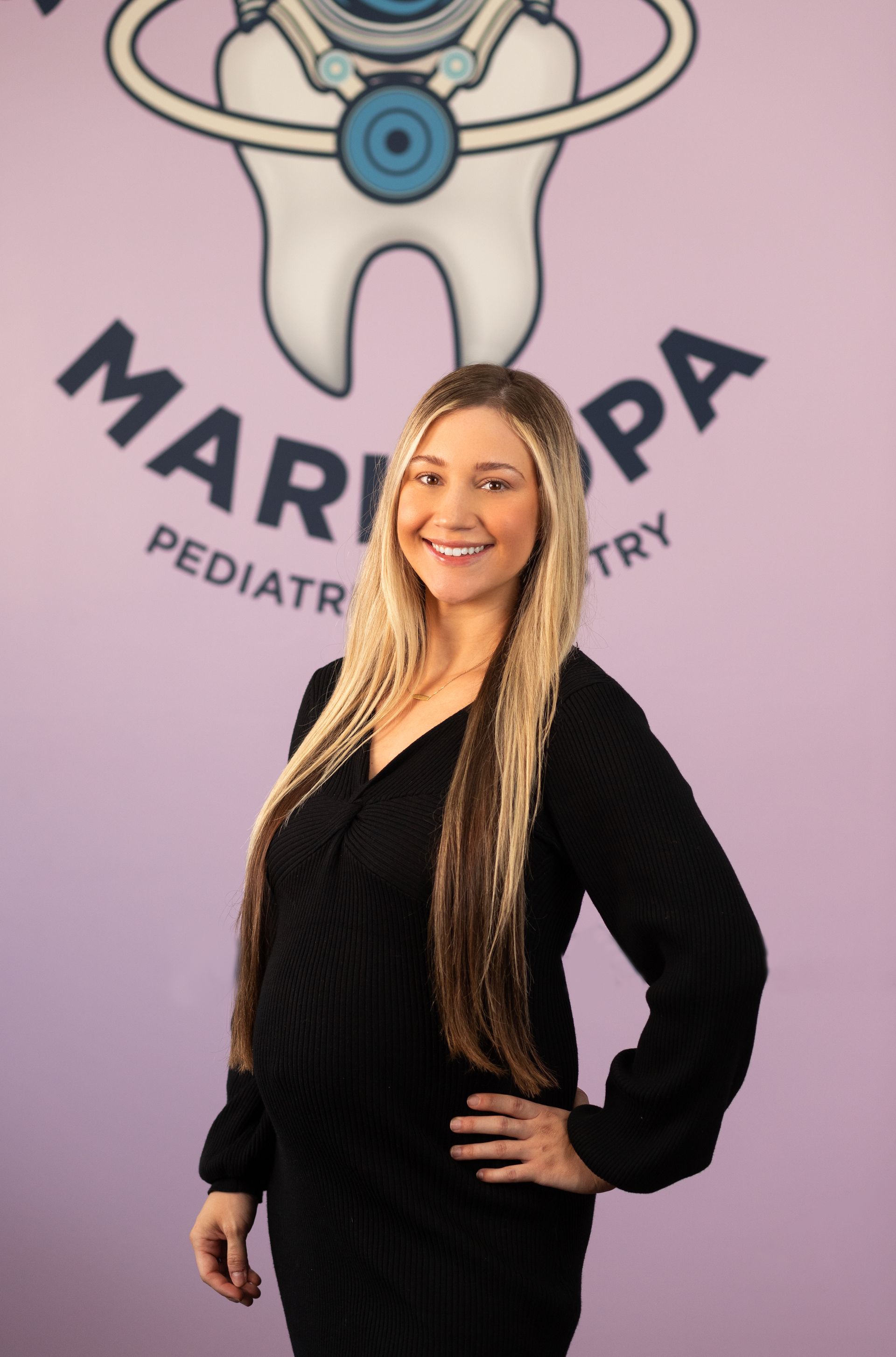 A woman standing in front of a maricopa pediatrics logo