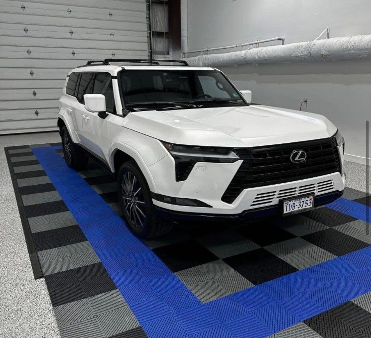White Lexus SUV parked indoors on a black-and-blue checkered floor in a garage