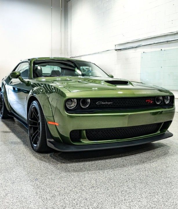Green Dodge Challenger parked indoors in a garage, front three-quarter view