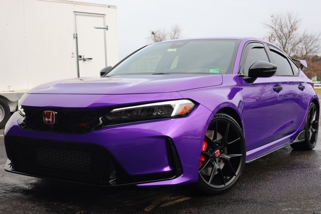 A person is cleaning a car with a red towel.