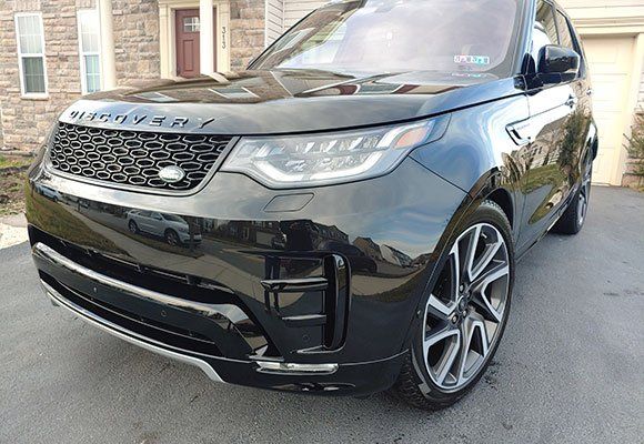 Black Land Rover Discovery parked on a paved driveway.