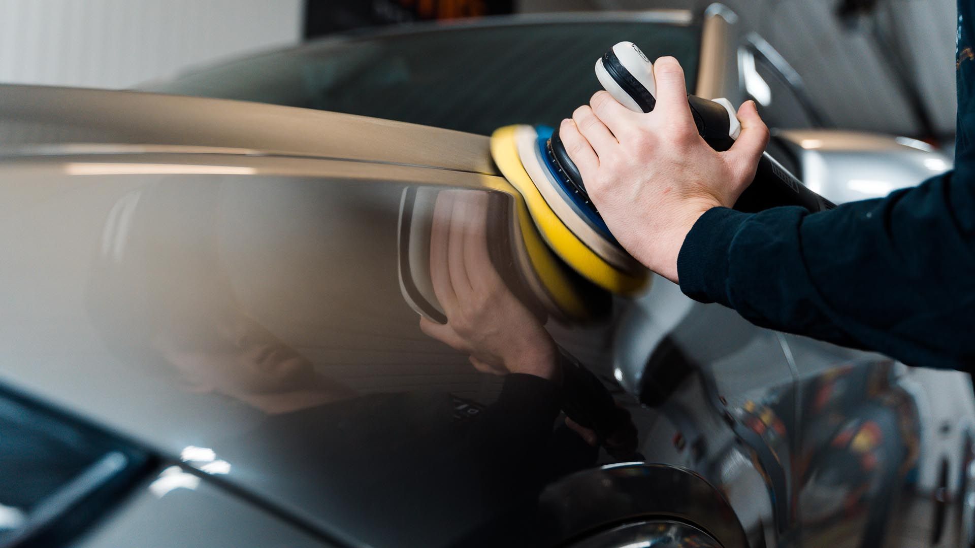 A person is polishing a car with a machine.
