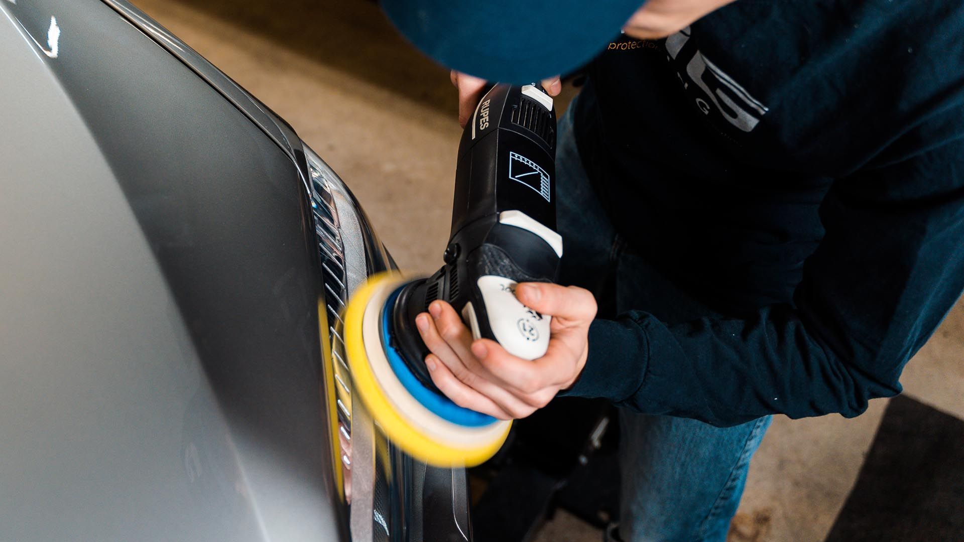 A person is polishing a car with a polisher.
