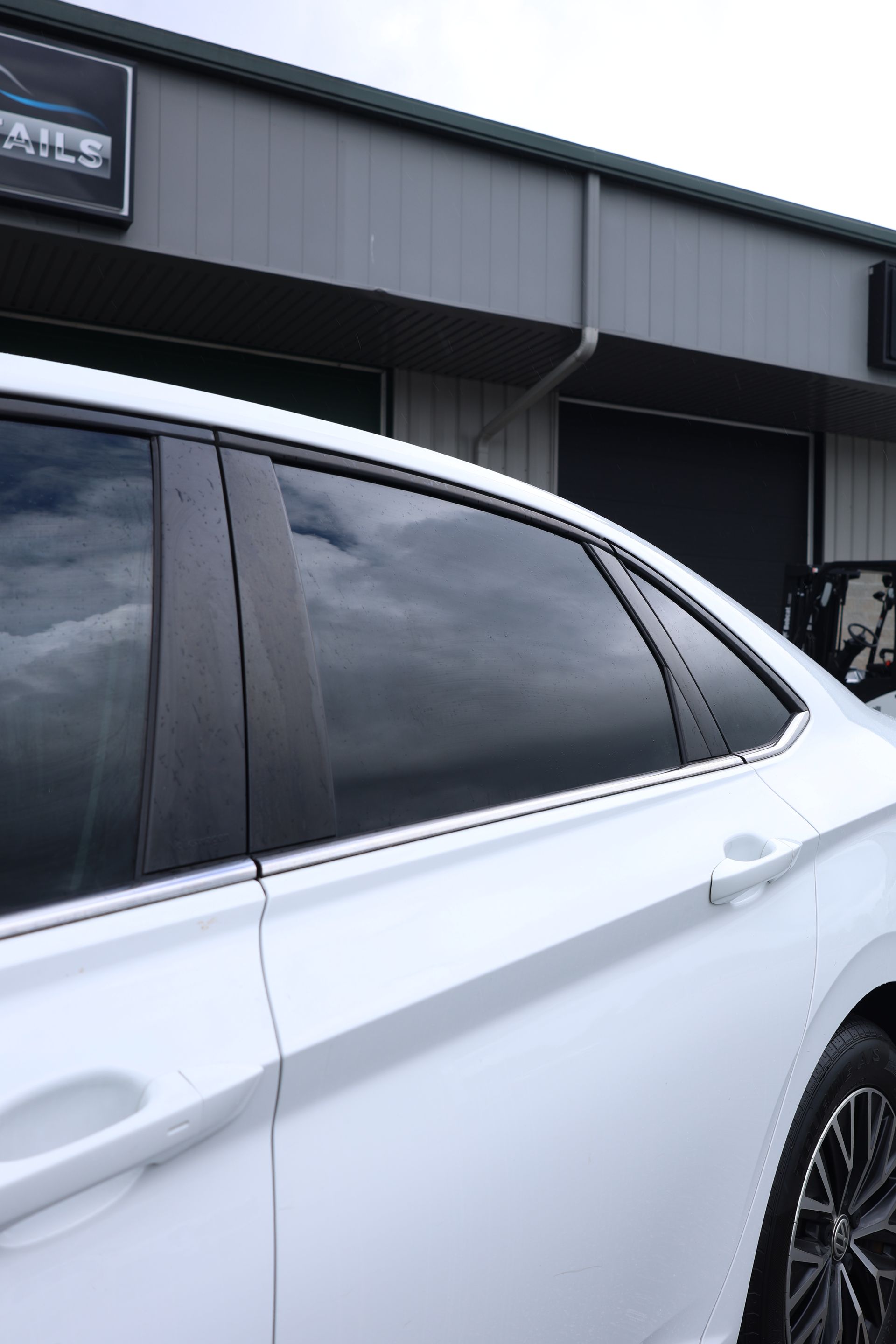 White car with tinted windows in front of a building.