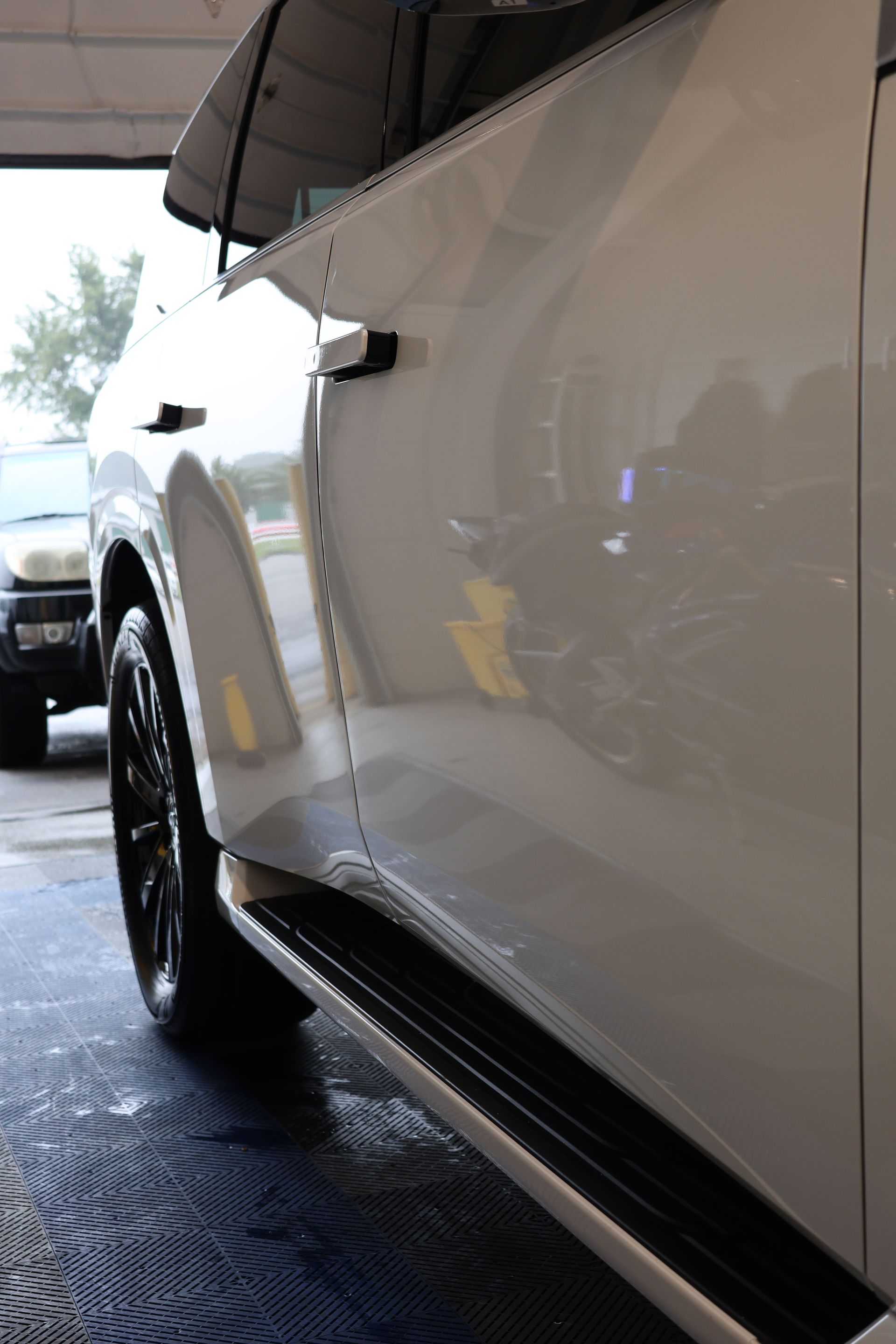 A person is holding a blue object in their hand in front of a car.