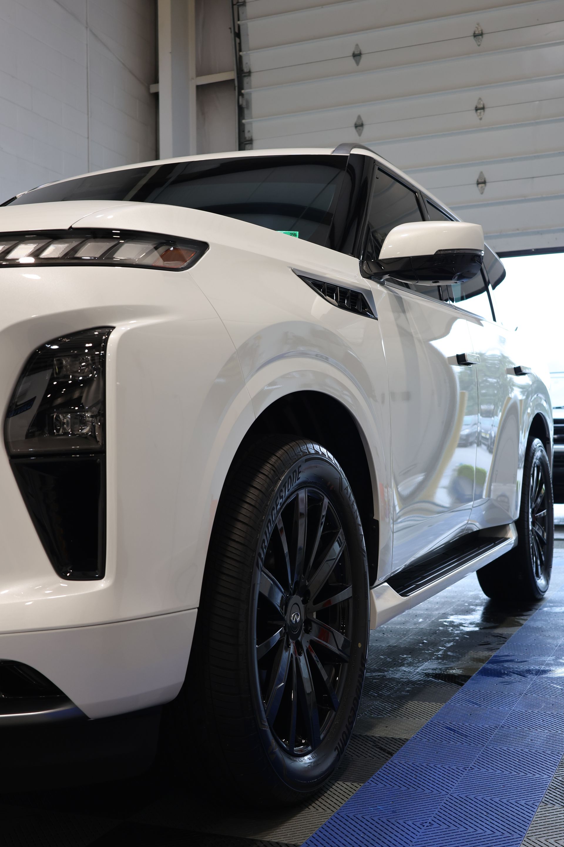 A person is polishing a black car with a blue sponge.