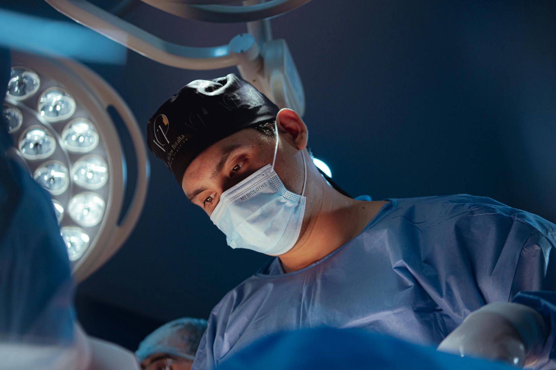 A surgeon wearing a mask is operating on a patient in an operating room.