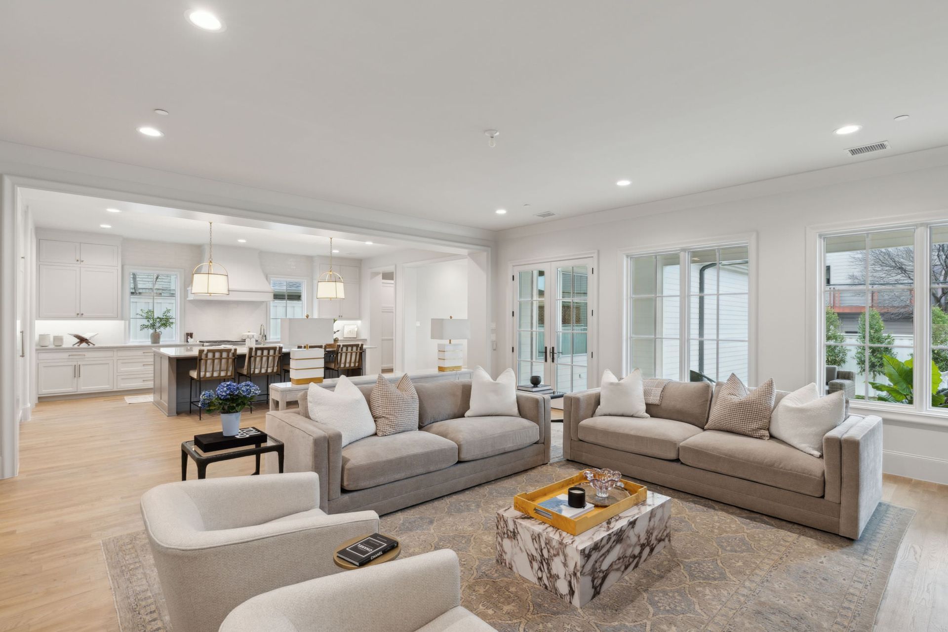 Spacious living room with gray sofas, white walls, and an open kitchen.
