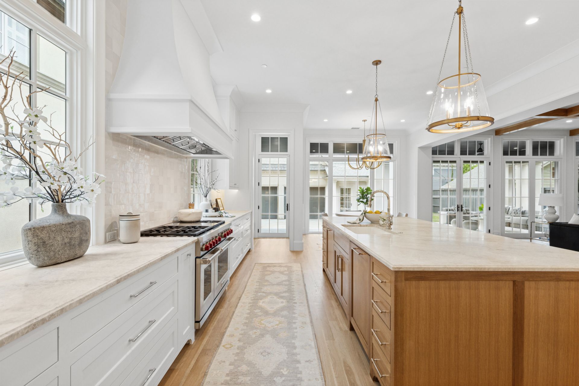 A kitchen with white cabinets and wooden cabinets and a large island.