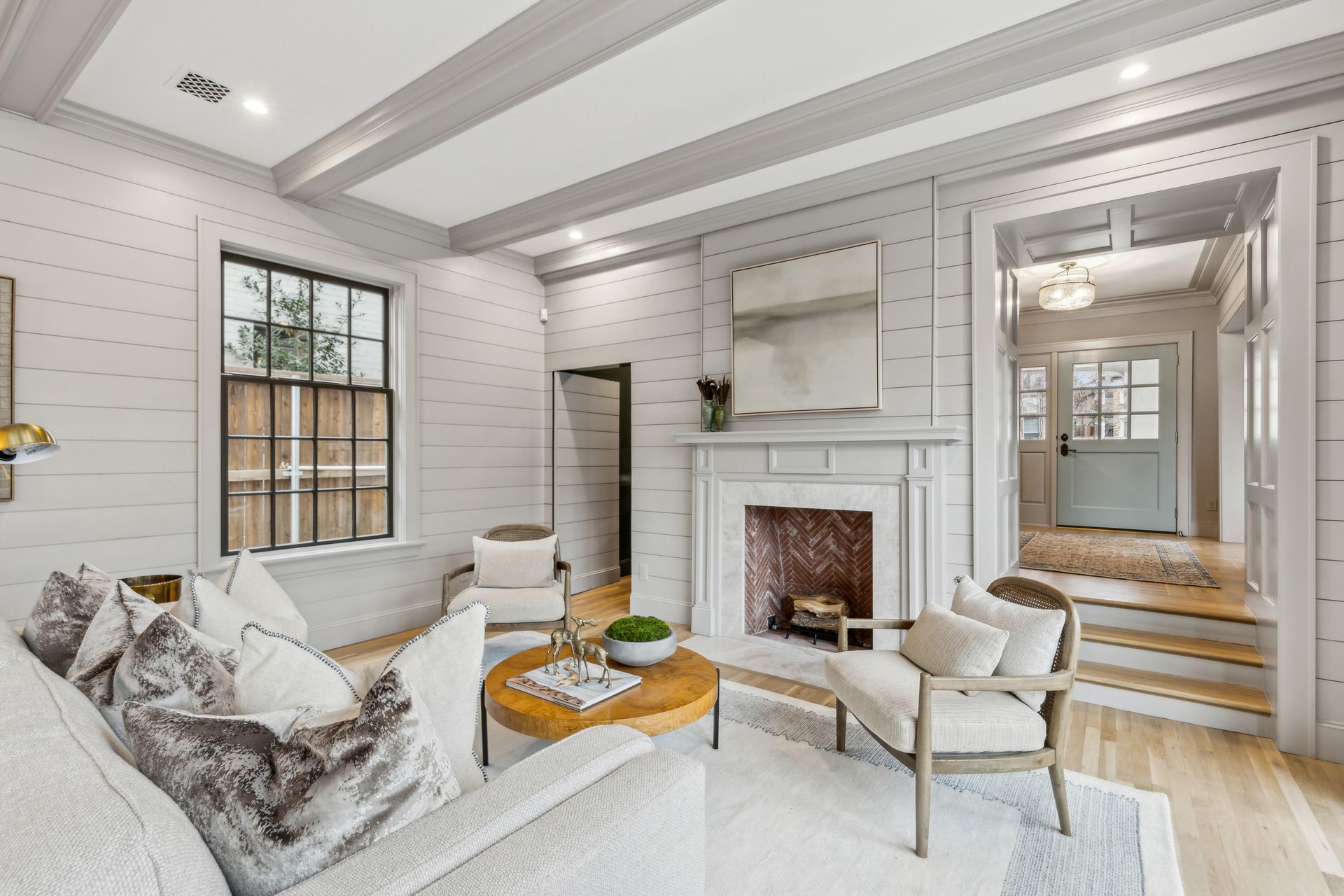 Living room with fireplace, gray walls, light wood floor, seating, and doorway.