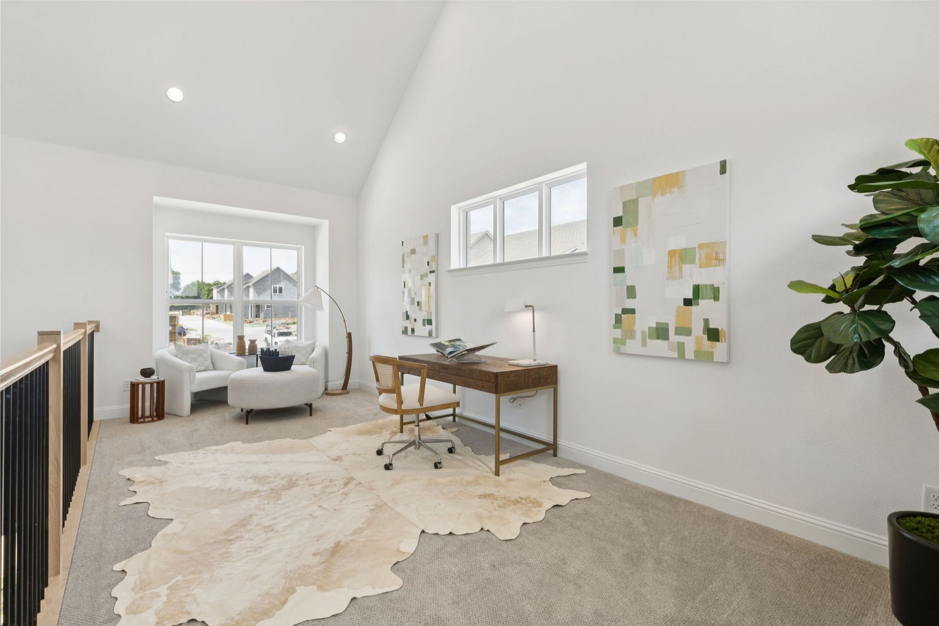 A bright home office with a desk, chair, and rug. White walls, large window, and a plant.