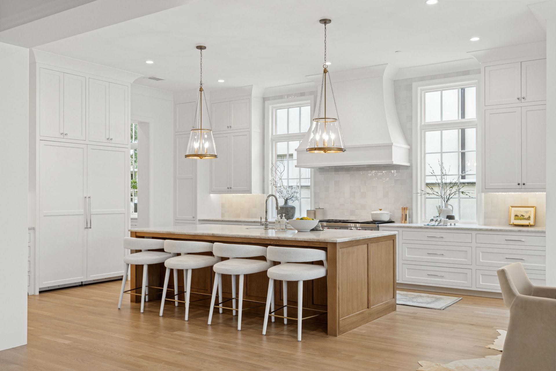 A kitchen with white cabinets , wooden floors , and a large island.