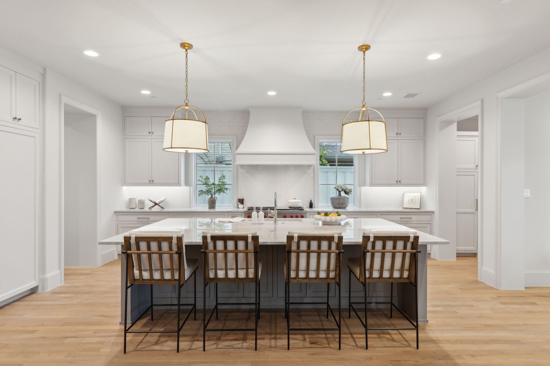 Modern white kitchen with island seating and gold pendant lights.