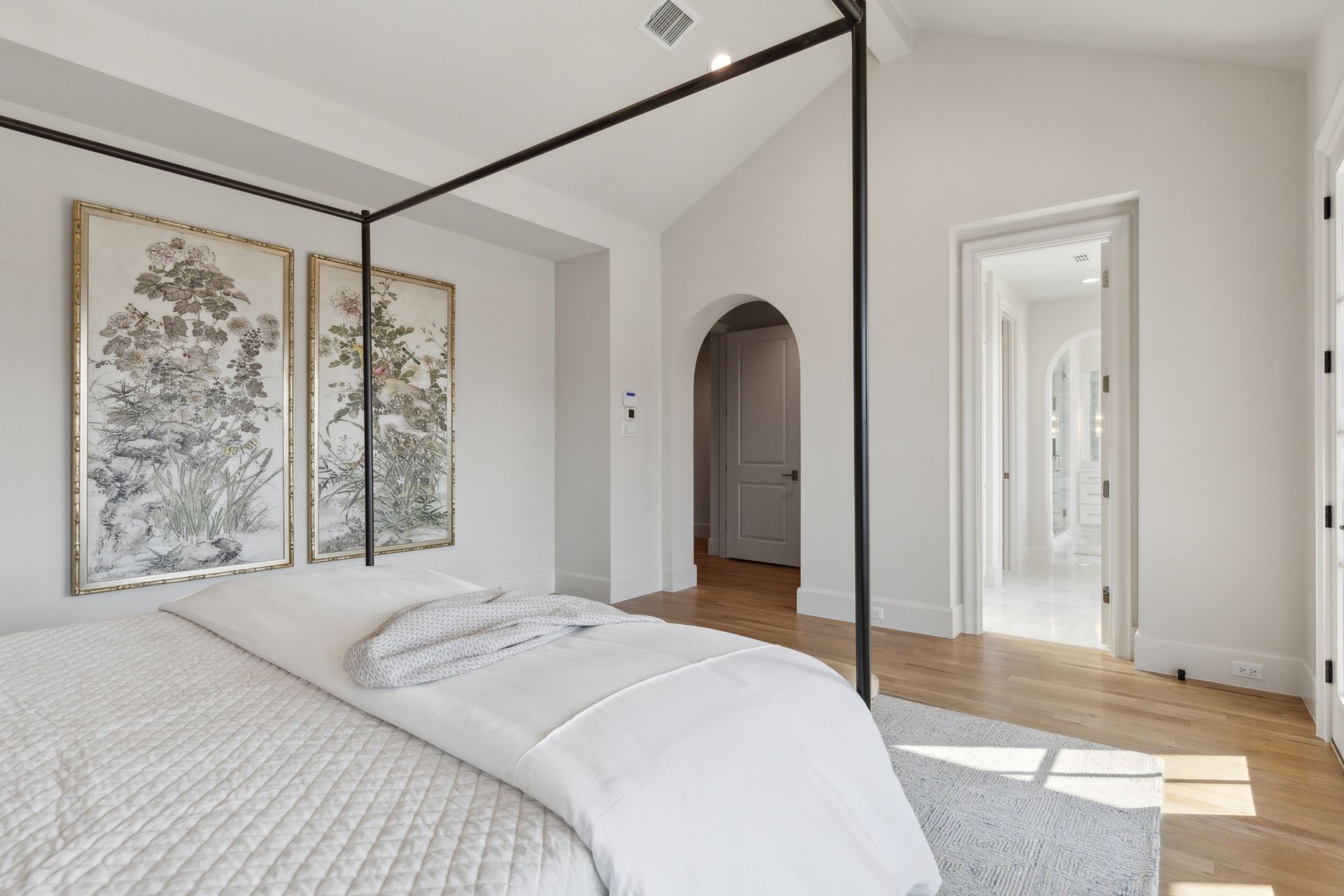 A bedroom with a canopy bed and two paintings on the wall.