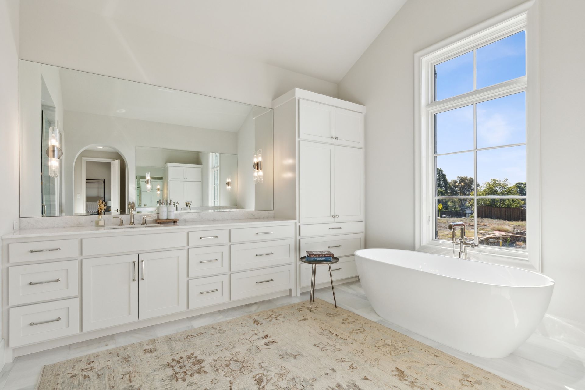 A bathroom with two sinks , a tub , and a large mirror.