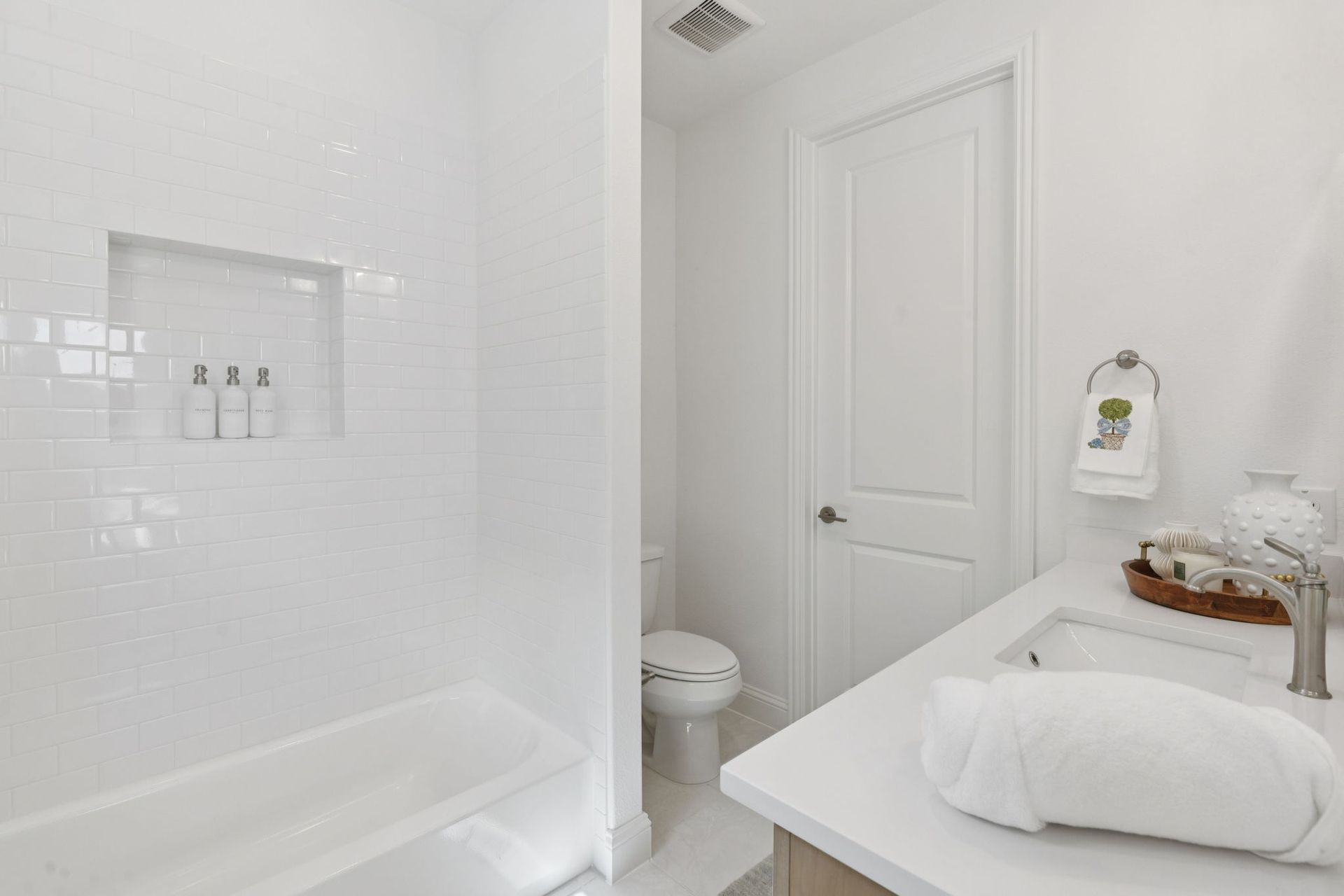 White bathroom with tub, sink, toilet, and door.