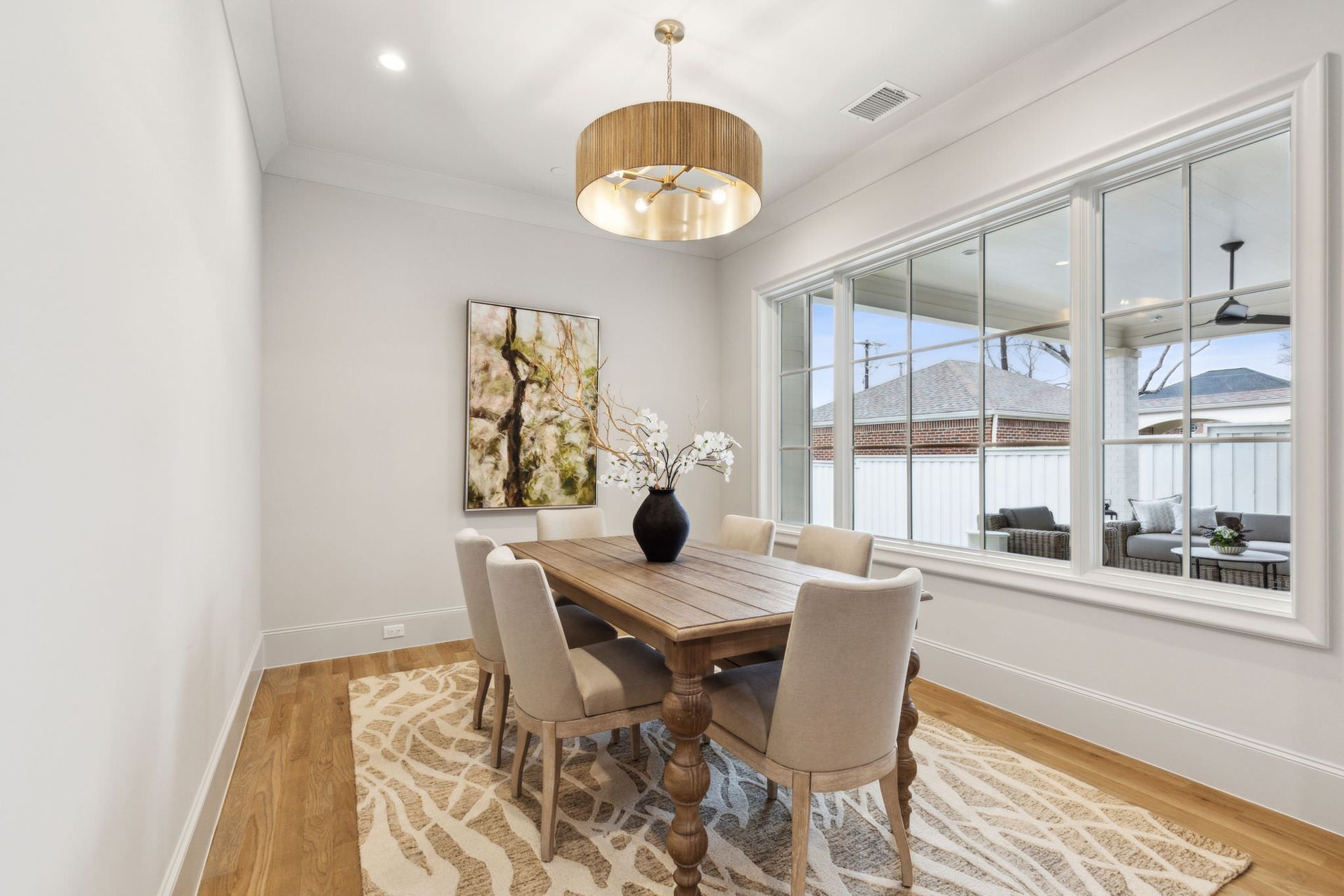 Dining room with table, chairs, artwork, rug, large window with outdoor view.