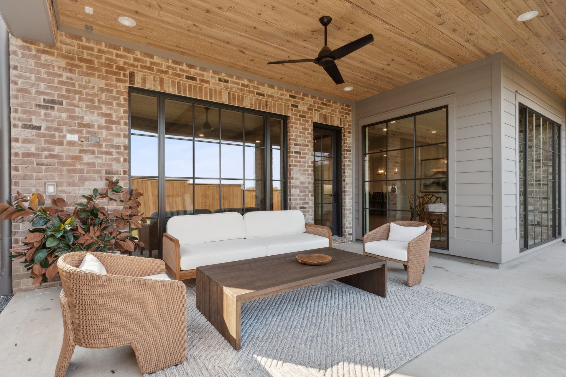 A patio with a couch , chairs , coffee table and ceiling fan.