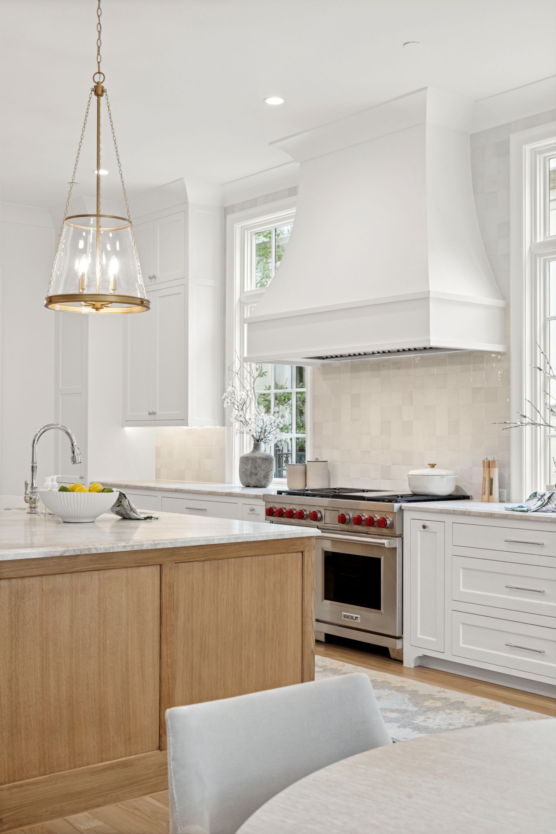 A kitchen with white cabinets , wooden cabinets , stainless steel appliances , a table and chairs.