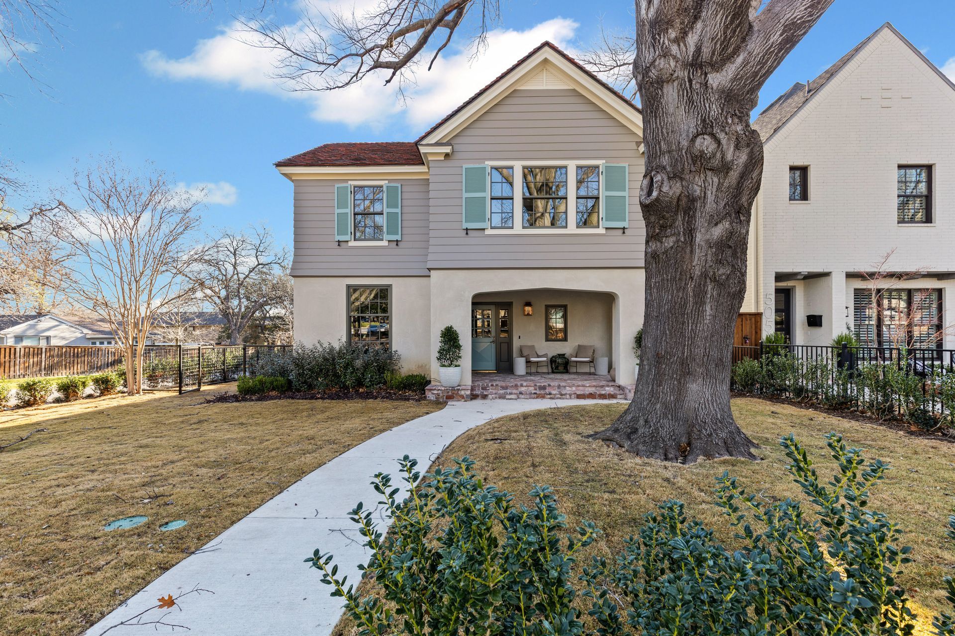 Two-story house with gray siding, aqua shutters, and a winding path to the front door.