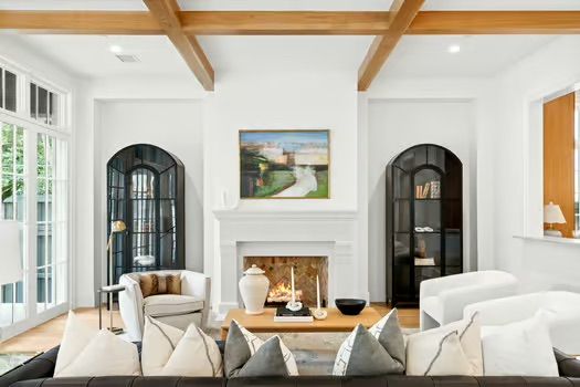 A living room with a fireplace , couch , chairs and a painting on the wall.