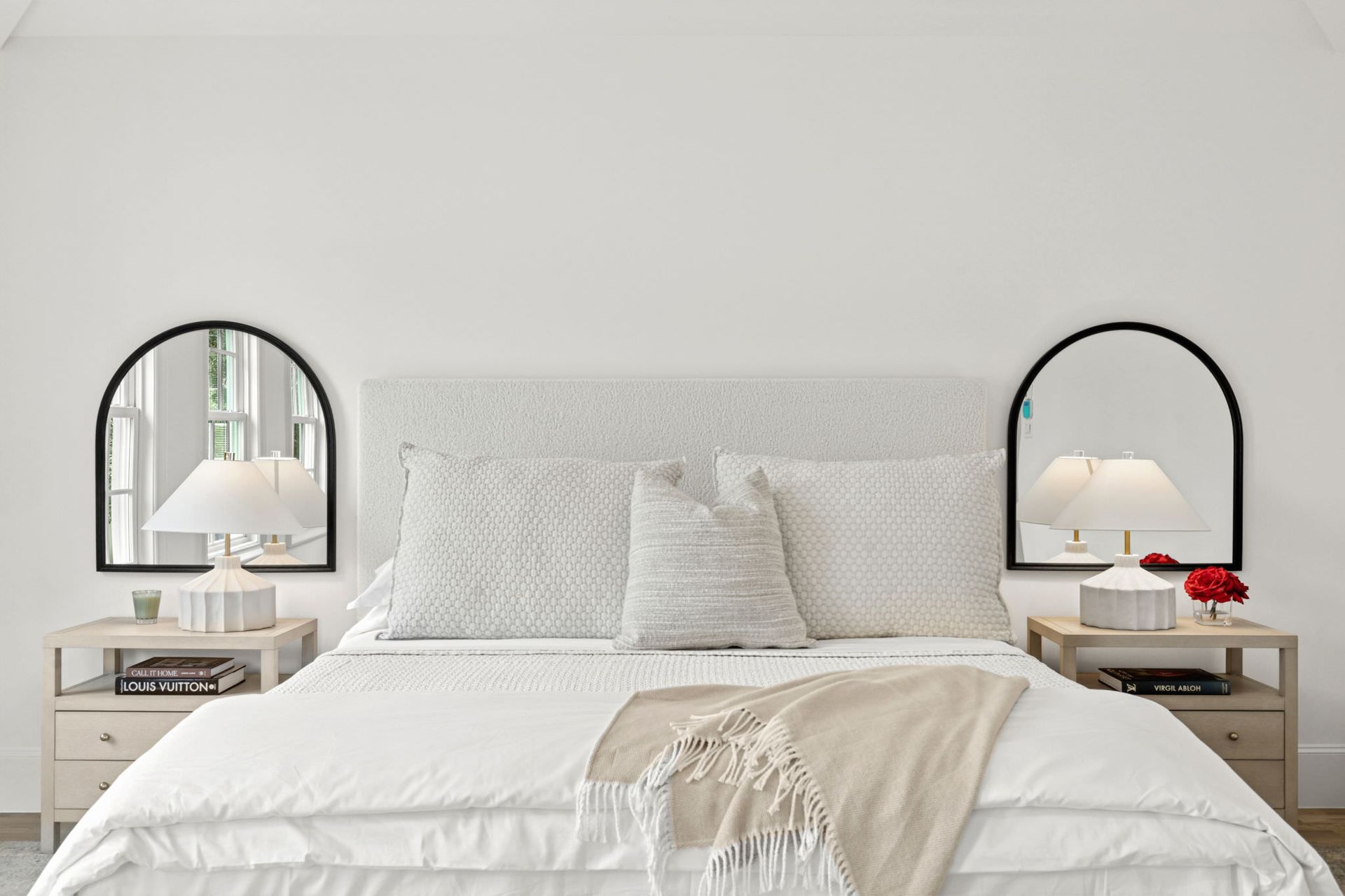 A bedroom with a bed , two nightstands , two mirrors and two lamps.