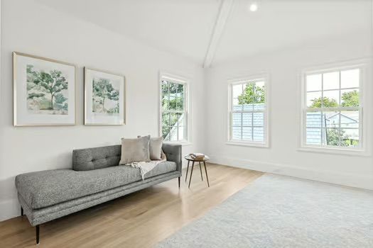 A living room with a couch and two windows.