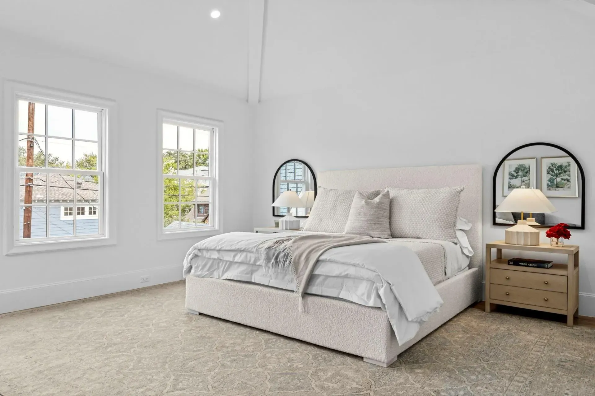 A bedroom with a bed , nightstand , and two windows.