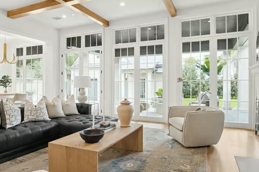 A living room with a couch , chair , coffee table and lots of windows.