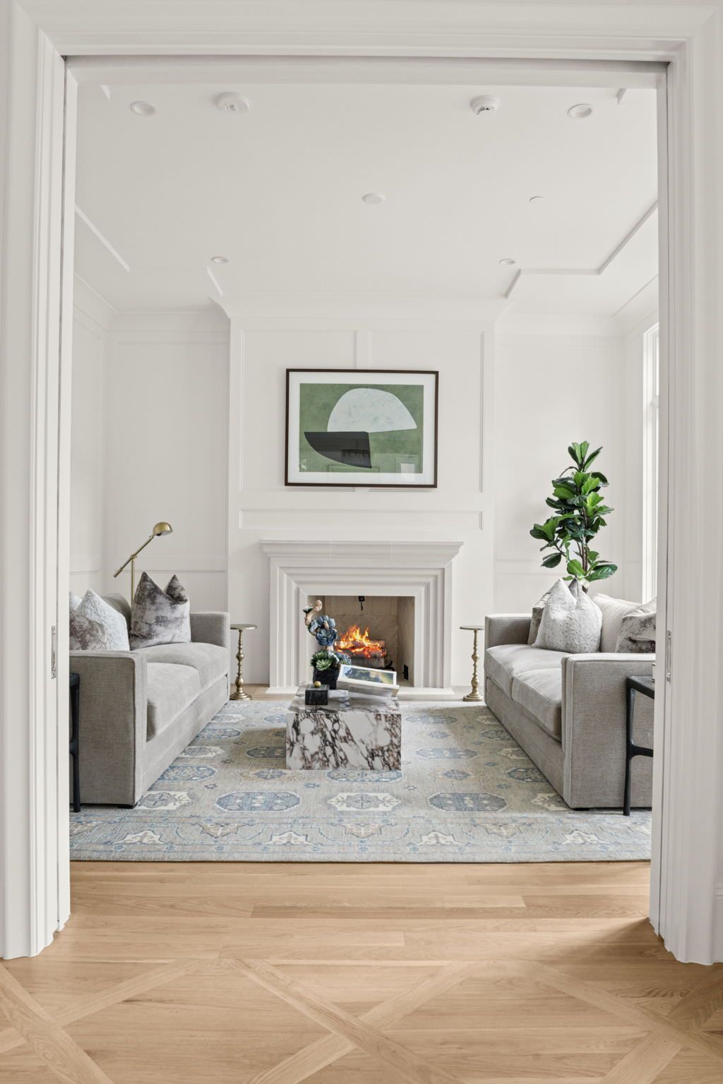 A living room with two couches , a fireplace and a rug.